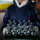 An employee carries a box of defective glass bottles to be recycled.